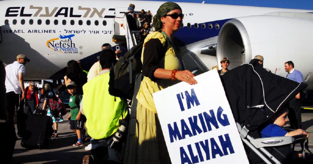 עולה אמריקאית לפני עליה למטוס אל על אוחזת בשלט 'I'm Making Aliyah'